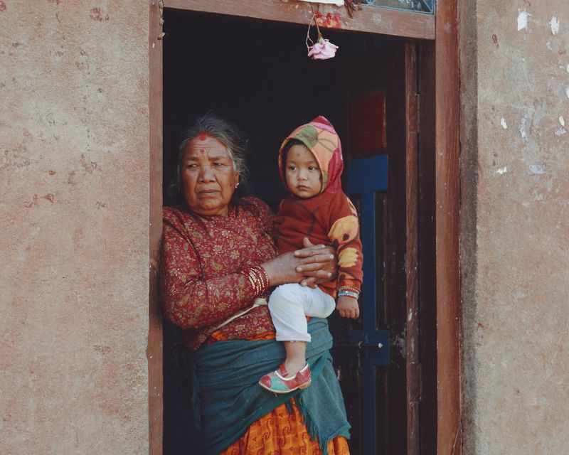 Elderly woman holding a young child in a doorway